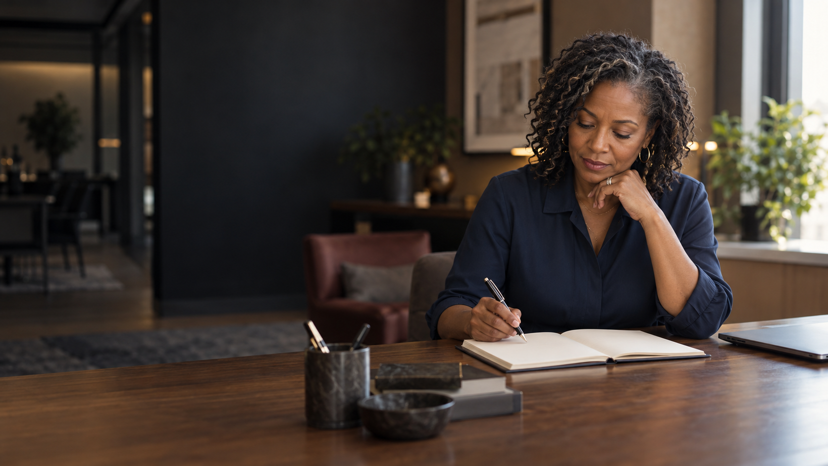 A business owner considering her next step with an open notebook at a wooden desk.